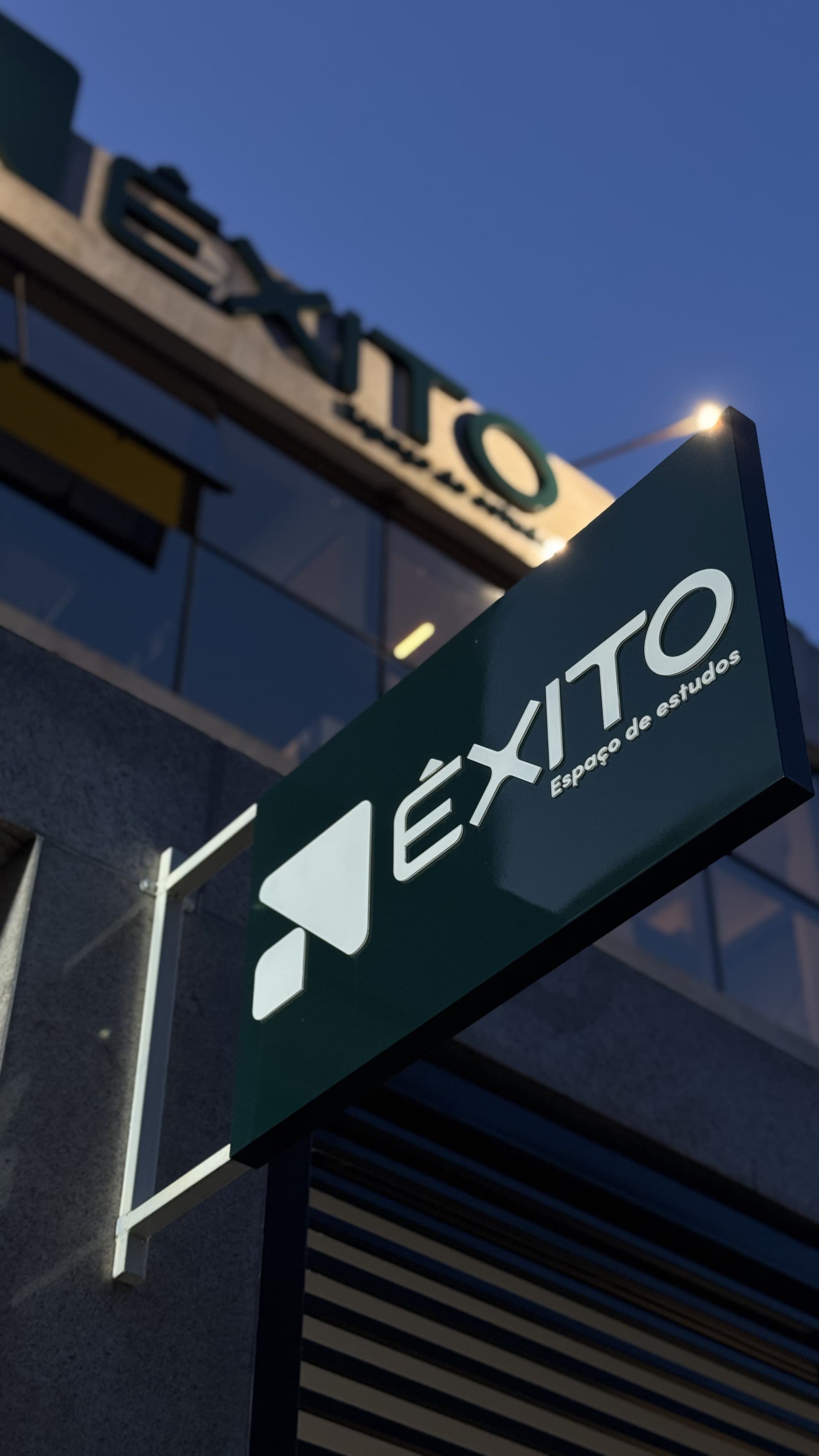 Placa suspensa Êxito iluminada ao entardecer com fundo de céu azul