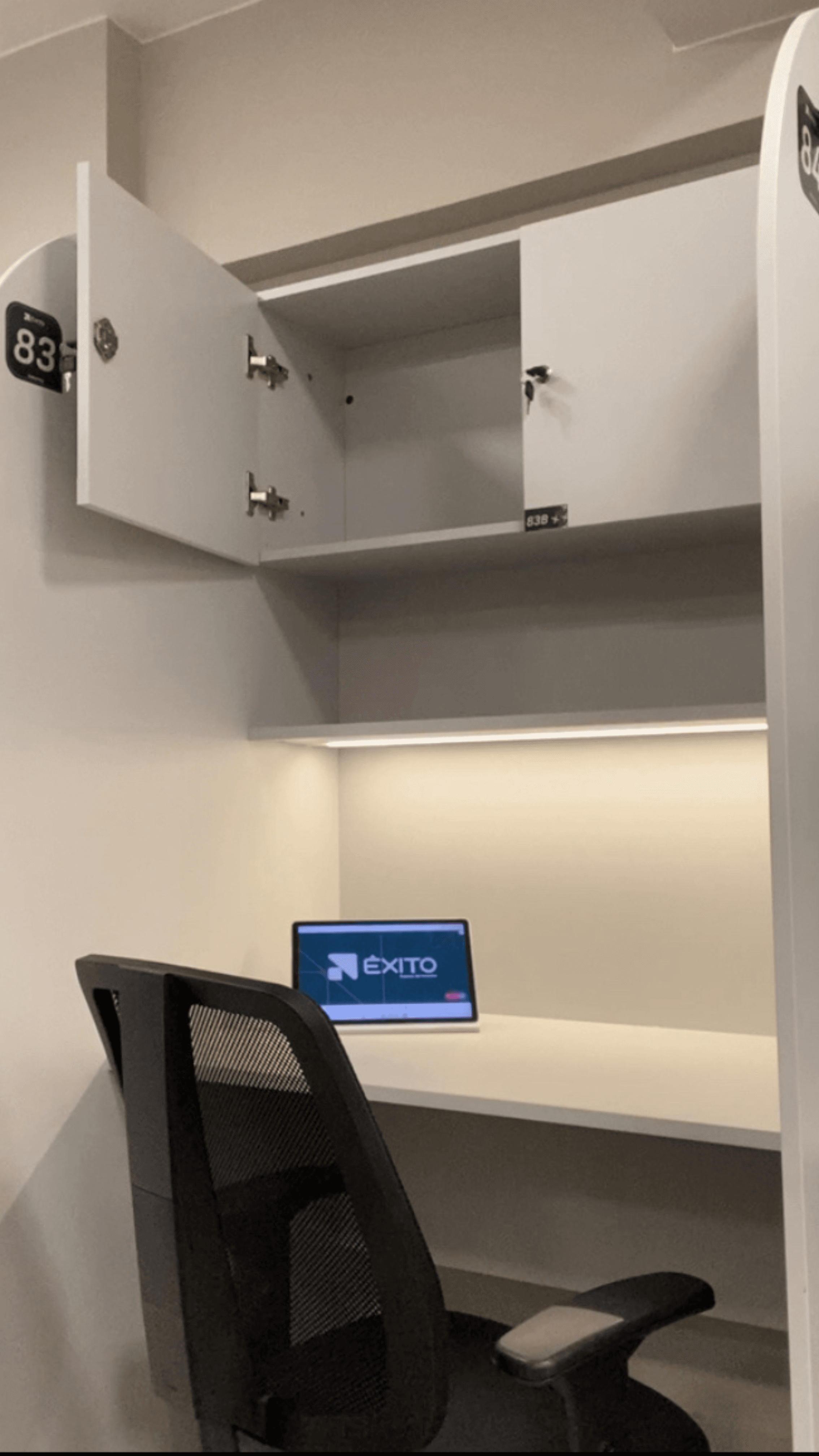 Interior da cabine fixa 83 com armário aberto e notebook com logo Êxito