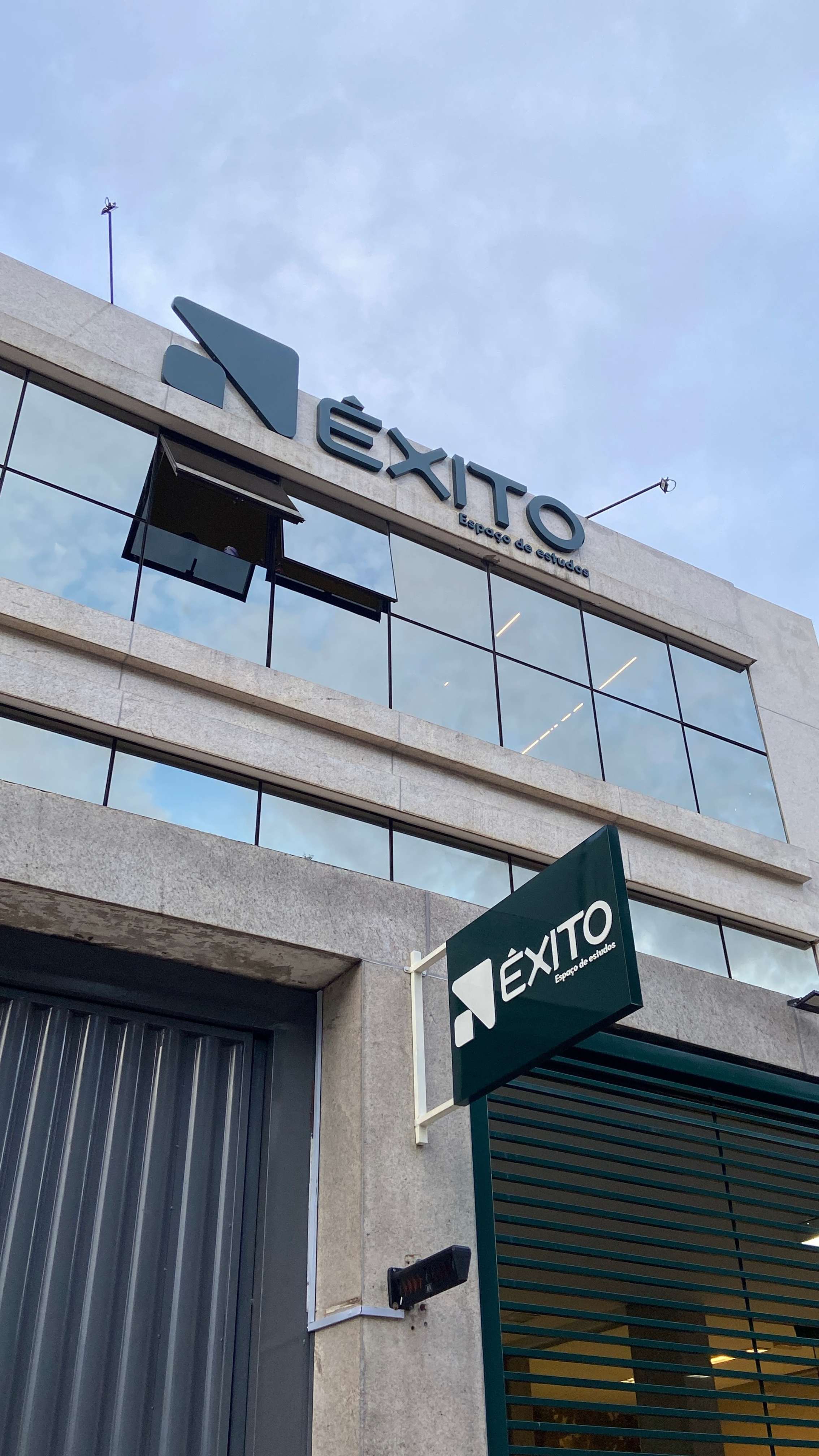 Fachada de dia com letreiro e placa suspensa Êxito, ângulo de baixo