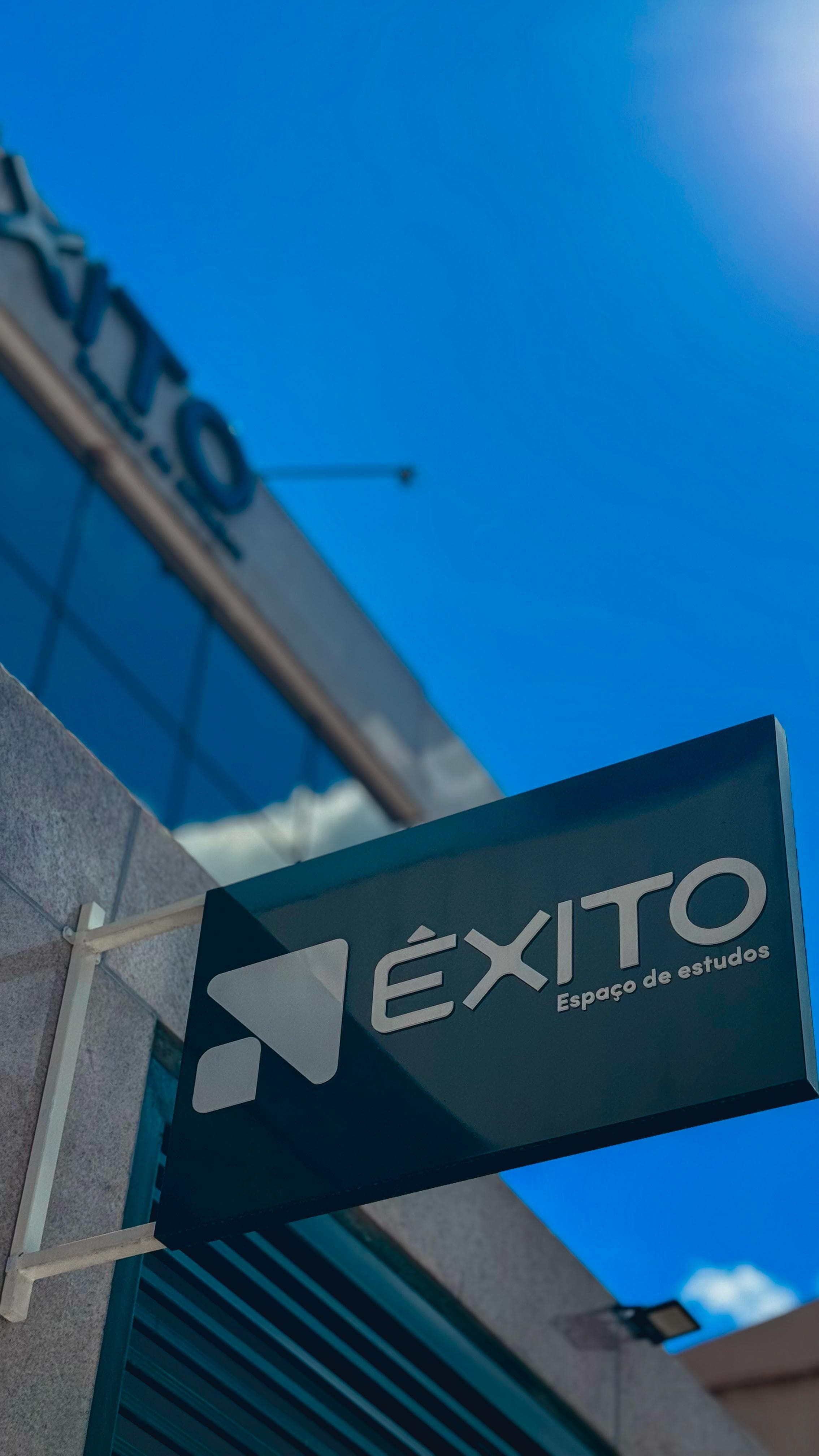 Close na placa Êxito suspensa com céu azul intenso